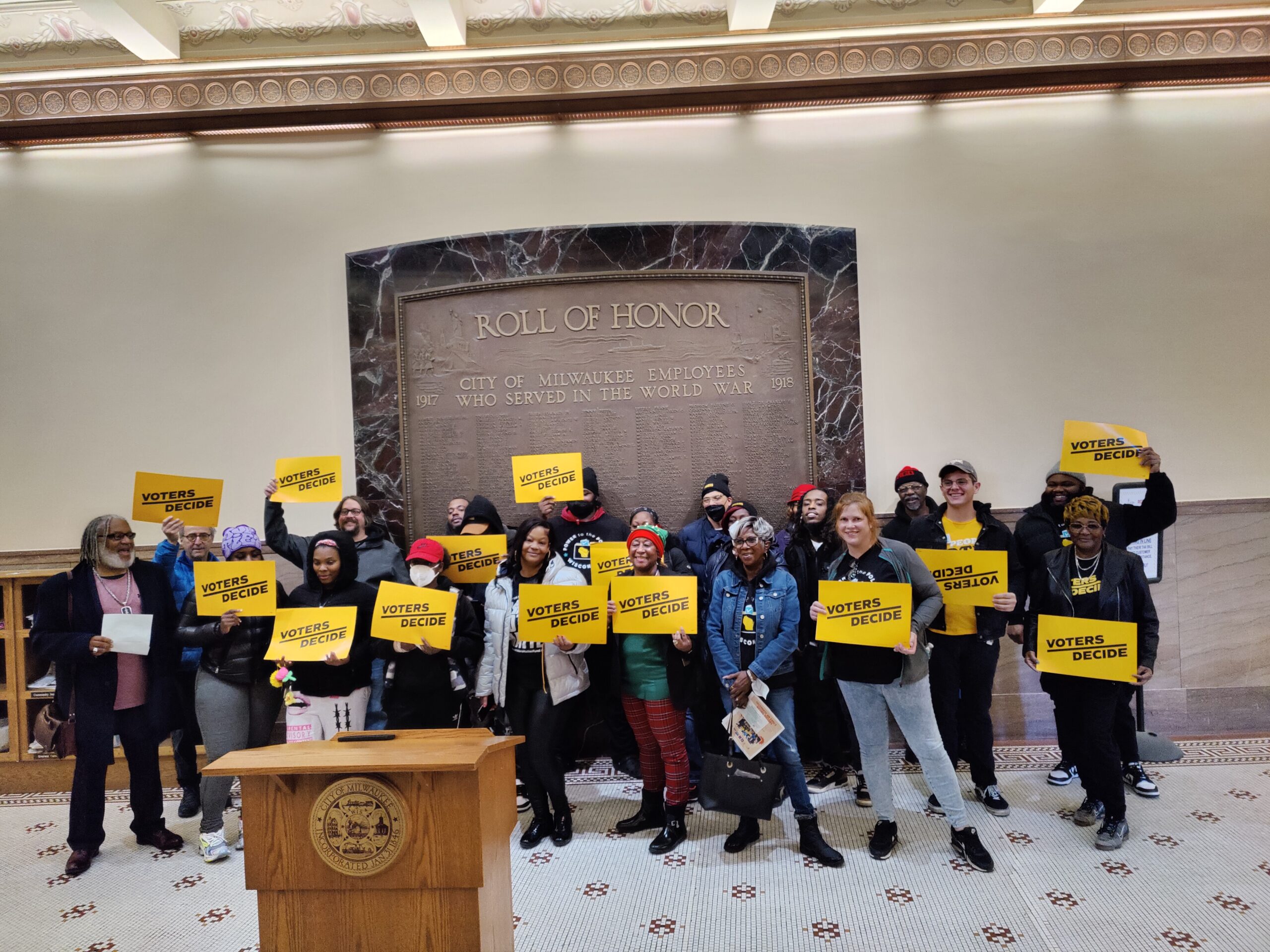 Photograph of ACLU of Wisconsin and coalition members holding Let People Vote signs in Milwaukee City Hall