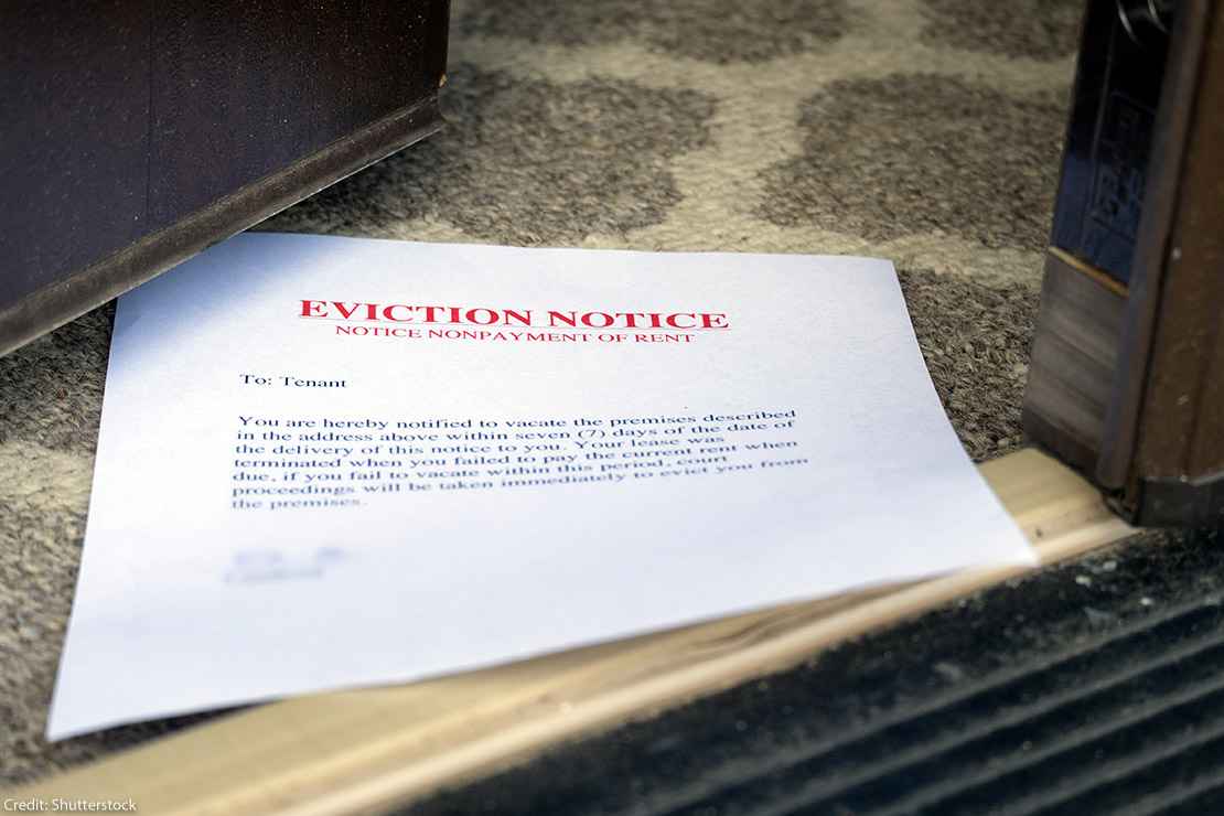 A stock photo of an eviction noticed, placed in an open door.