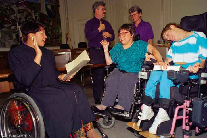 Judy Heumann, center wheelchair, is sworn in as U.S. Assistant Secretary for Special Education and Rehabilitative Service by Judge Gail Bereola, left, on June 29, 1993. Standing at left is Berkeley Mayor Loni Hancock with sign language interpreter...