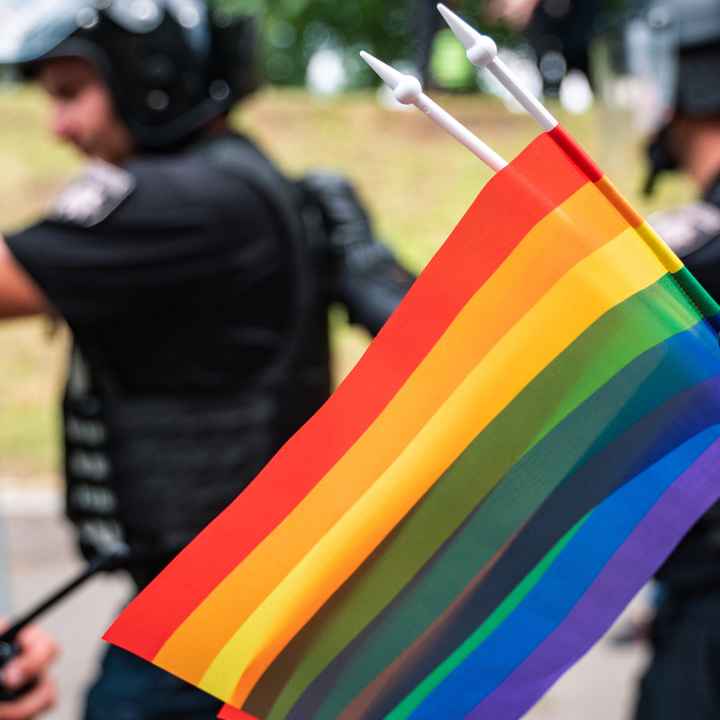 LGBTQ flag with police in the background.